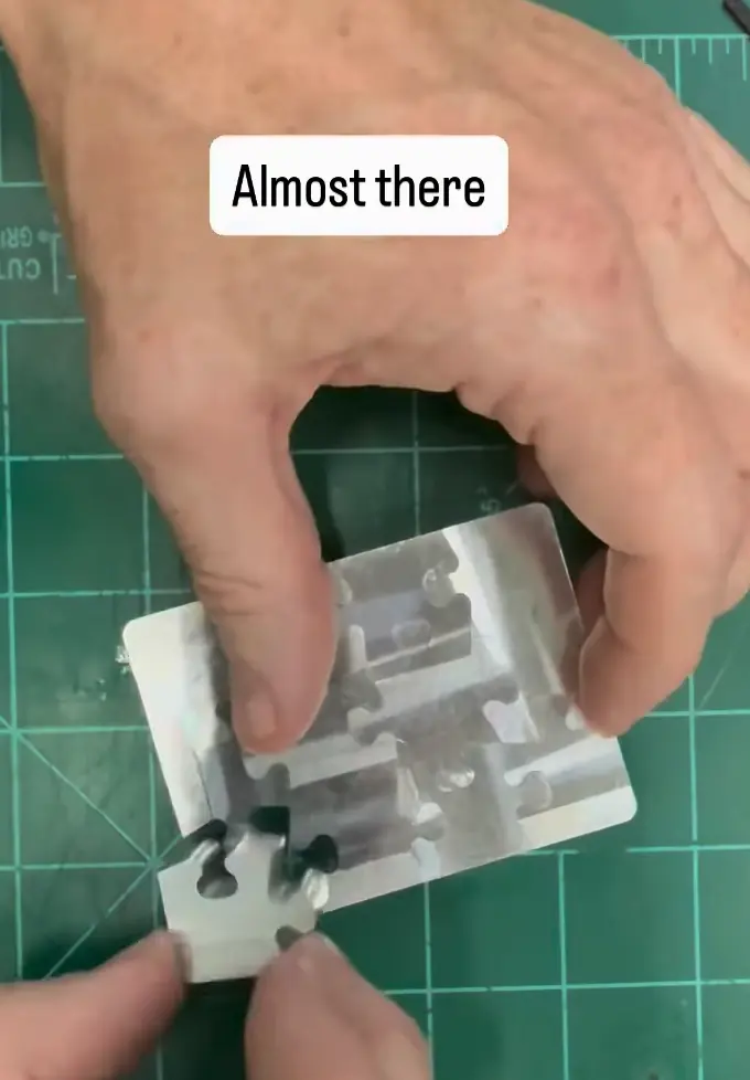 Hand fitting a piece into a stainless steel NEUTRINO prototype on a cutting mat, captioned “Almost there”